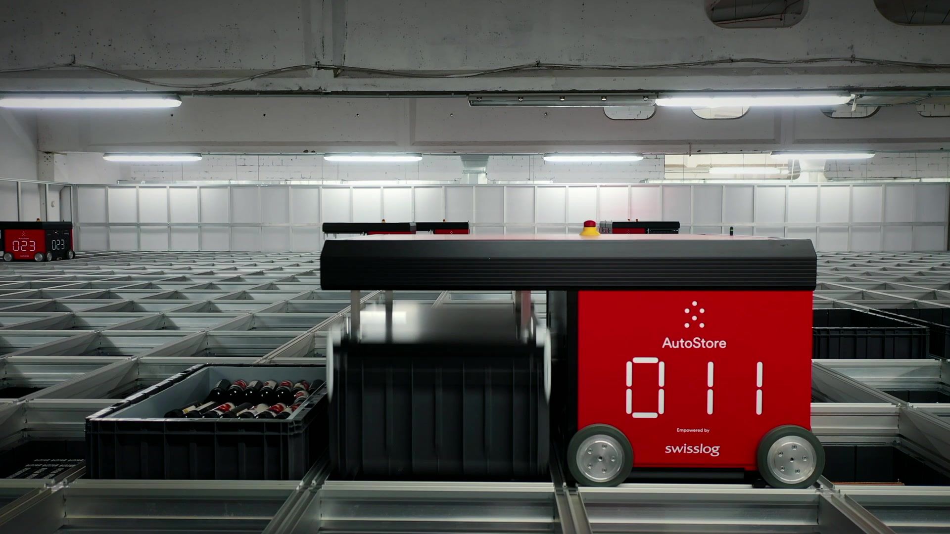 AutoStore-Anlage: ein Roboter fährt mit einem Behälter über das Raster